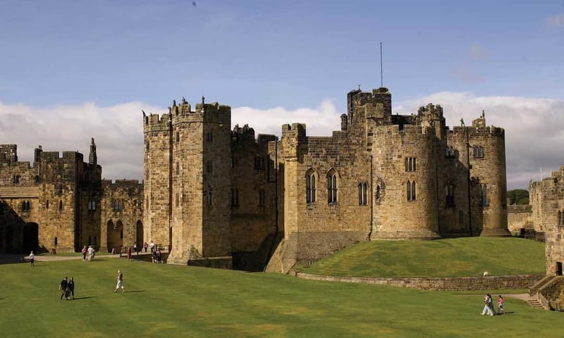 Edinburgh: Harry Potter and English Castles Tour in Spanish - Bamburgh Castle beside the beach